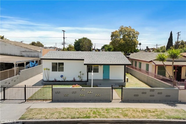 view of front of home featuring a shingled roof, a gate, a fenced front yard, and stucco siding