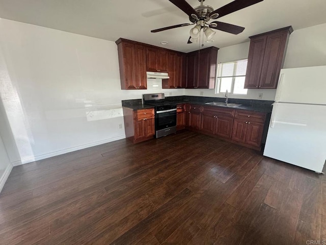 kitchen with dark countertops, a sink, stainless steel gas range, freestanding refrigerator, and under cabinet range hood