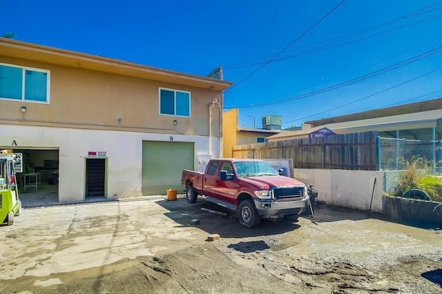 view of home's exterior with an attached garage, fence, driveway, and stucco siding