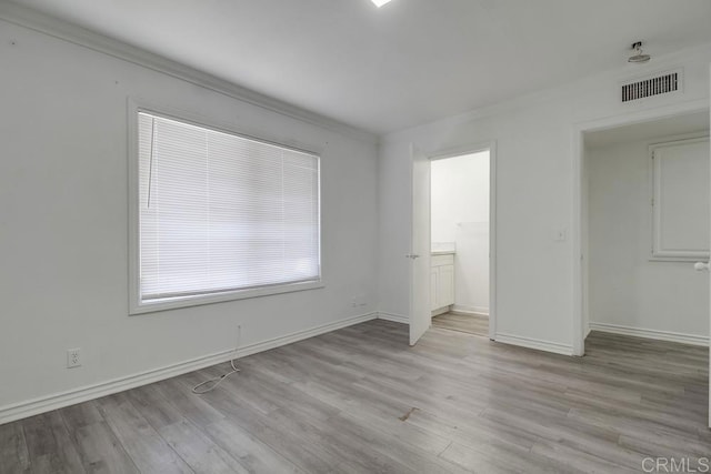 unfurnished bedroom with baseboards, visible vents, ensuite bathroom, and light wood finished floors