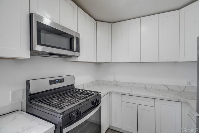 kitchen with light stone counters, white cabinets, and stainless steel appliances