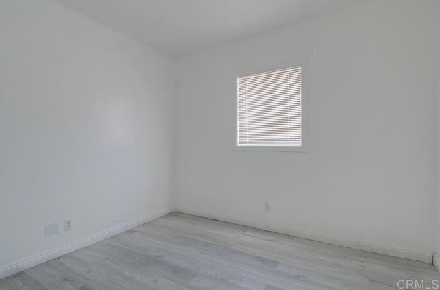 spare room with baseboards and light wood-style flooring