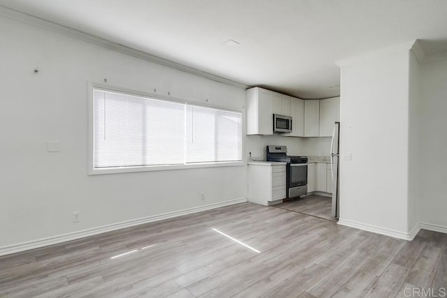 kitchen featuring baseboards, light countertops, white cabinets, light wood finished floors, and stainless steel appliances