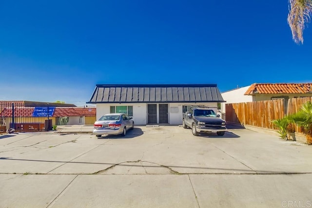 view of front of property featuring fence, a standing seam roof, metal roof, and stucco siding