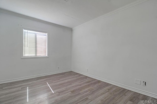 spare room with baseboards, ornamental molding, and wood finished floors
