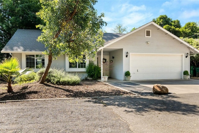 view of front of property with driveway, a shingled roof, and a garage