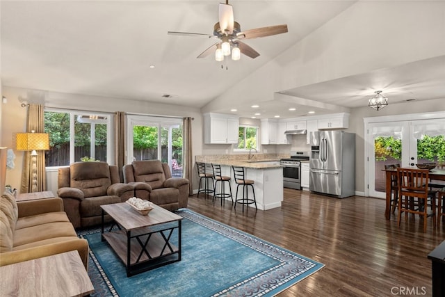 living area with visible vents, vaulted ceiling, dark wood finished floors, baseboards, and ceiling fan with notable chandelier