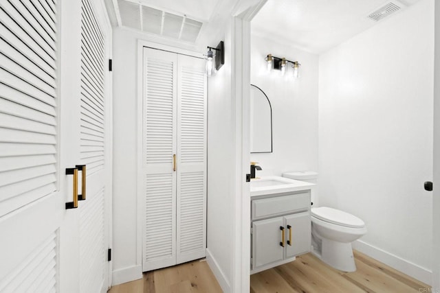 bathroom featuring visible vents, vanity, wood finished floors, toilet, and baseboards