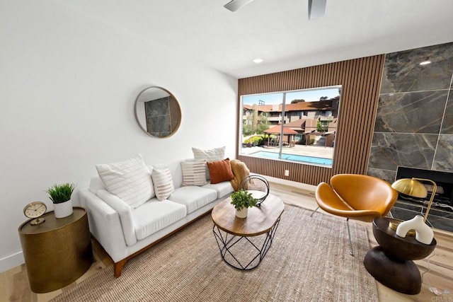living area with baseboards, ceiling fan, and wood finished floors