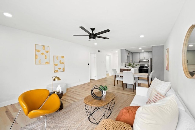living area with a ceiling fan, baseboards, recessed lighting, and light wood-style floors