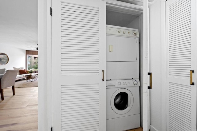 laundry room featuring stacked washer and clothes dryer, light wood finished floors, and laundry area