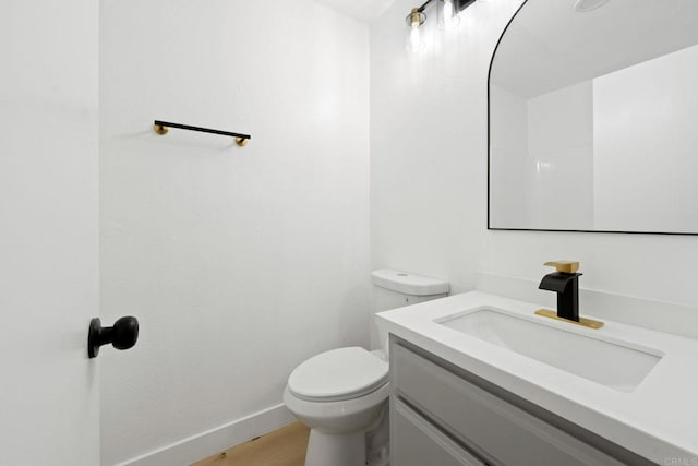 bathroom with toilet, baseboards, and vanity