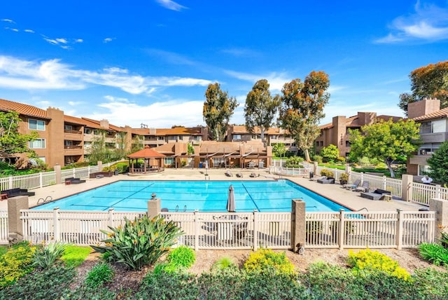 pool featuring a patio, fence, and a residential view