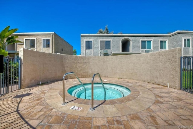 view of swimming pool featuring fence and a community hot tub