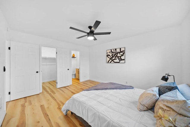 bedroom with a walk in closet, a ceiling fan, baseboards, a closet, and light wood finished floors