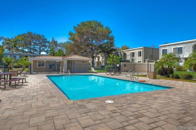 pool with fence, a patio area, and a residential view