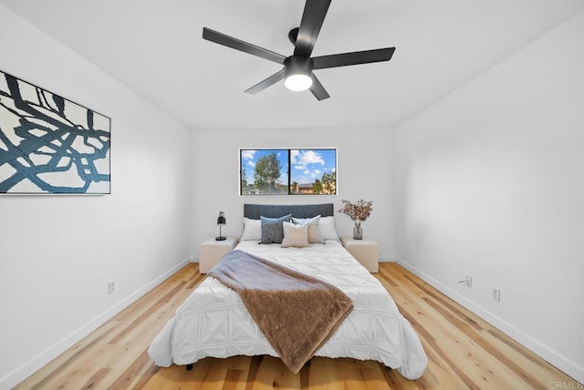 bedroom with baseboards, a ceiling fan, and light wood-style flooring