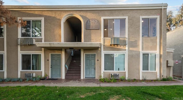 view of front of house with central AC, a front lawn, and stucco siding