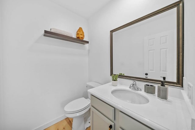 half bathroom featuring toilet, wood finished floors, and vanity