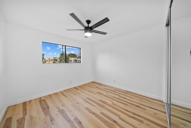 spare room featuring baseboards, ceiling fan, and light wood finished floors