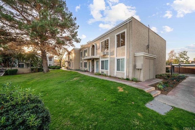 back of property featuring fence, stucco siding, and a yard