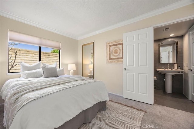 bedroom with visible vents, a sink, crown molding, and carpet floors