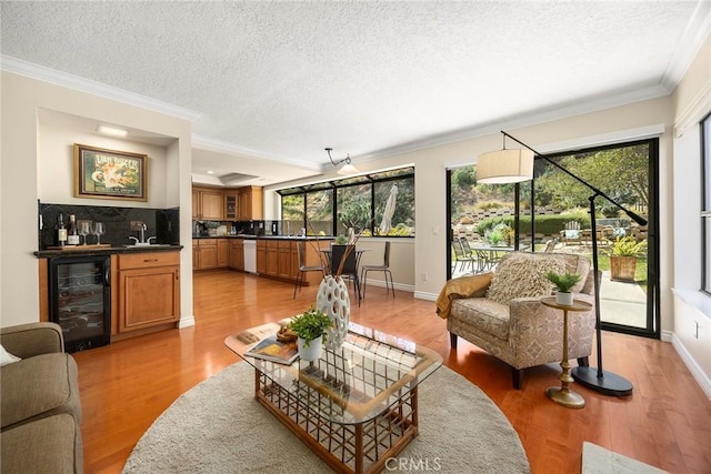 living room with indoor wet bar, beverage cooler, a textured ceiling, and crown molding