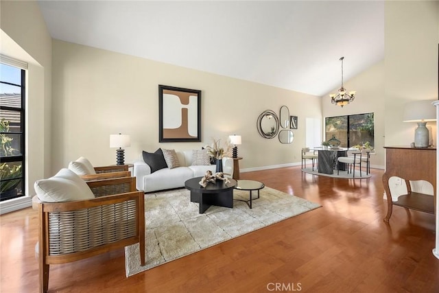 living room with baseboards, high vaulted ceiling, a notable chandelier, and wood finished floors