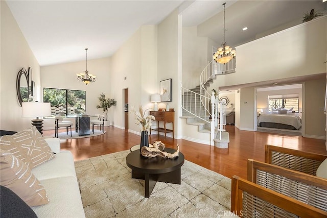 living area with plenty of natural light, stairs, wood finished floors, and a chandelier