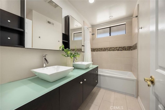bathroom with shower / bath combo with shower curtain, visible vents, a sink, and tile patterned flooring
