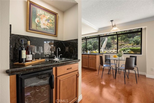 bar with a sink, tasteful backsplash, beverage cooler, and crown molding