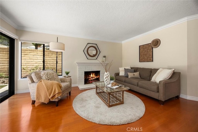 living area featuring crown molding, a textured ceiling, wood finished floors, and a fireplace