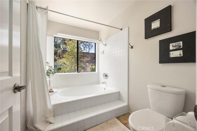 bathroom with tiled shower / bath combo and toilet