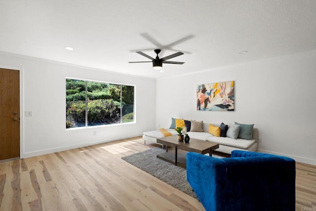 living room with crown molding, a ceiling fan, baseboards, and light wood-style floors