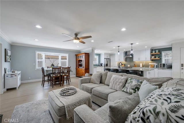 living room with recessed lighting, ornamental molding, light wood-style floors, and baseboards