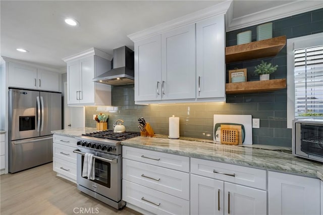 kitchen featuring open shelves, wall chimney exhaust hood, stainless steel appliances, white cabinetry, and decorative backsplash