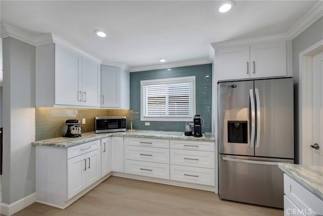 kitchen featuring decorative backsplash, stainless steel appliances, ornamental molding, and white cabinetry