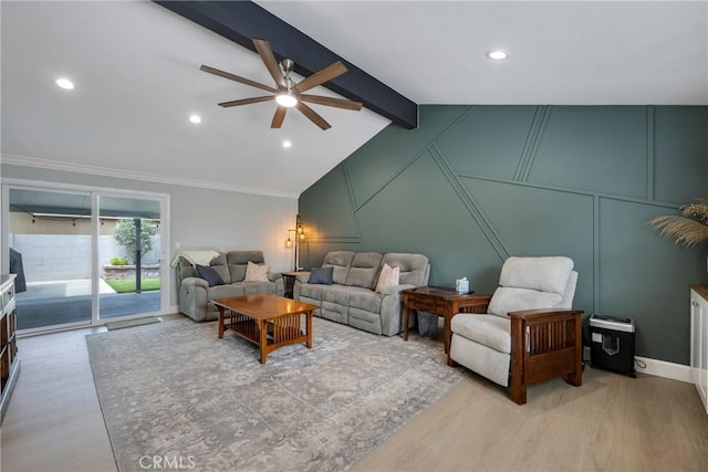 living room featuring ornamental molding, a decorative wall, lofted ceiling with beams, a ceiling fan, and light wood finished floors