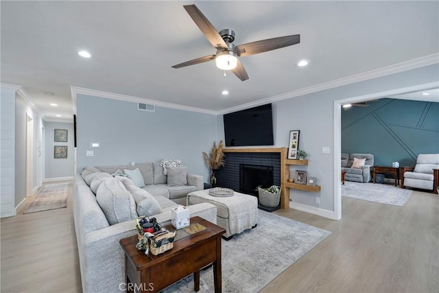 living area with crown molding, a ceiling fan, light wood-type flooring, and visible vents