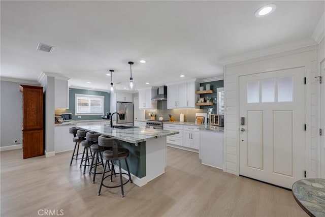 kitchen with visible vents, crown molding, wall chimney exhaust hood, and appliances with stainless steel finishes
