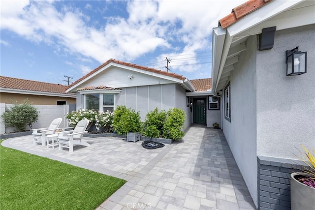 exterior space featuring a tiled roof, a patio, fence, and stucco siding