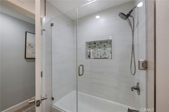 full bathroom featuring baseboards and bath / shower combo with glass door