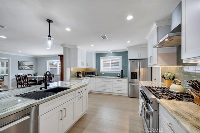 kitchen featuring appliances with stainless steel finishes, a sink, tasteful backsplash, visible vents, and ornamental molding