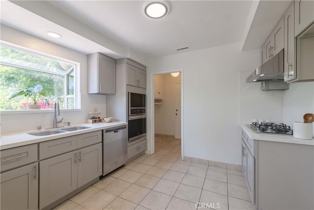 kitchen featuring visible vents, gray cabinets, under cabinet range hood, a sink, and appliances with stainless steel finishes