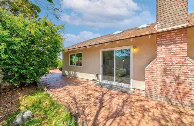 rear view of property with a patio area, stucco siding, and a chimney