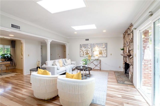 living room with a skylight, a stone fireplace, light wood-style flooring, and visible vents