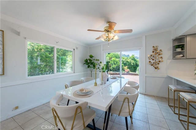 dining area with light tile patterned flooring, ceiling fan, ornamental molding, and a healthy amount of sunlight