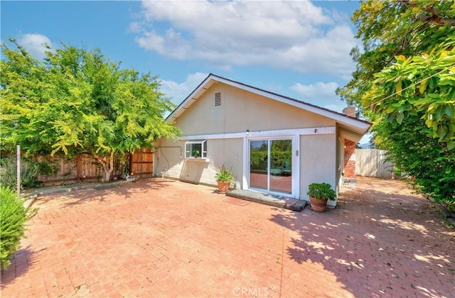 back of property featuring a patio area, stucco siding, a chimney, and fence