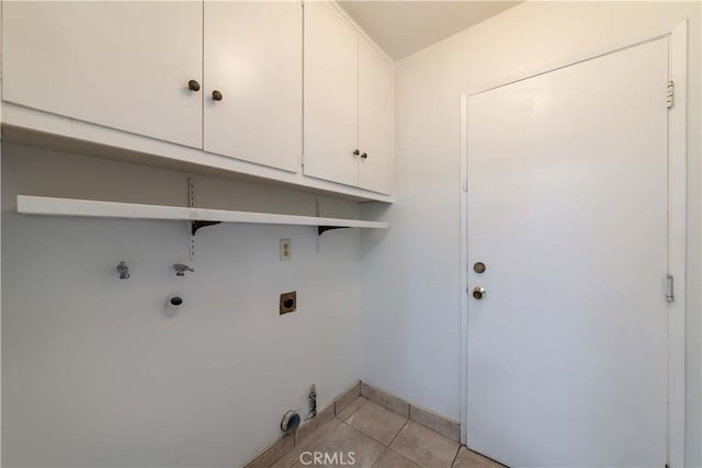 laundry room with hookup for an electric dryer, hookup for a gas dryer, cabinet space, baseboards, and light tile patterned flooring