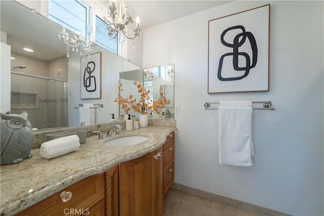 bathroom with vanity, baseboards, tile patterned floors, a shower stall, and a notable chandelier